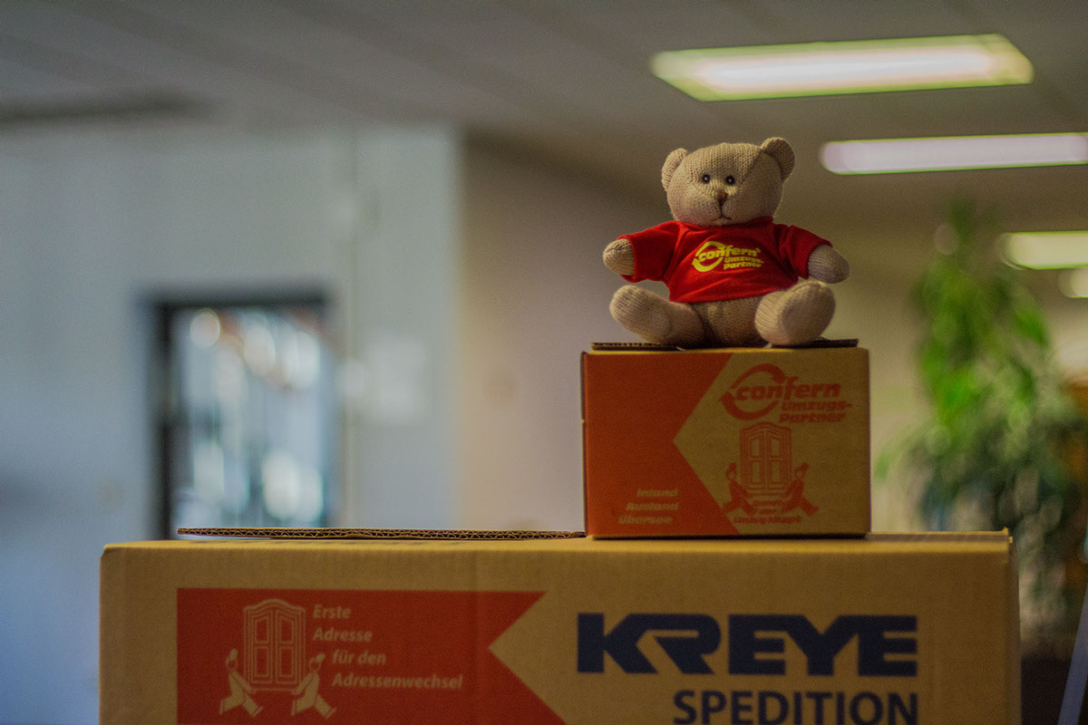 Das Bild zeigt Umzugskartons der Spedition Kreye und einen Stoffteddybären